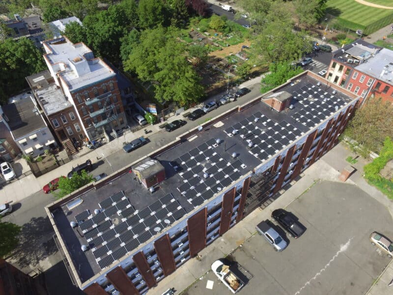 Aerial view of solar panels on black roof of brick apartment building